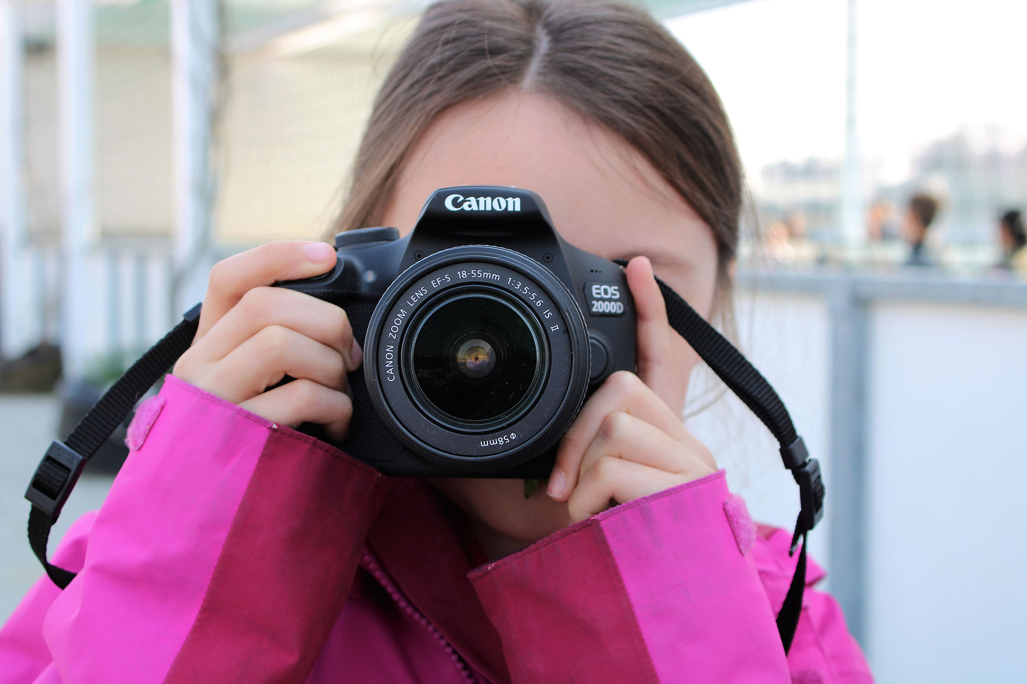 Una bambina che scatta una foto e ha il viso coperto dalla macchina fotografica.