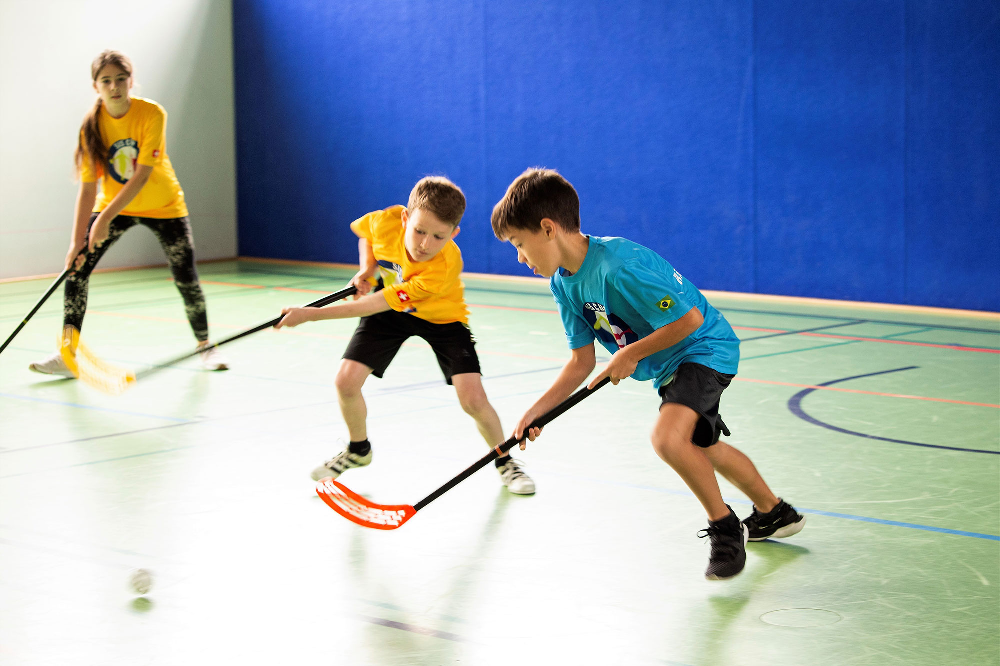 Due bambini mentre si sfidano per il possesso di palla dentro a una palestra.