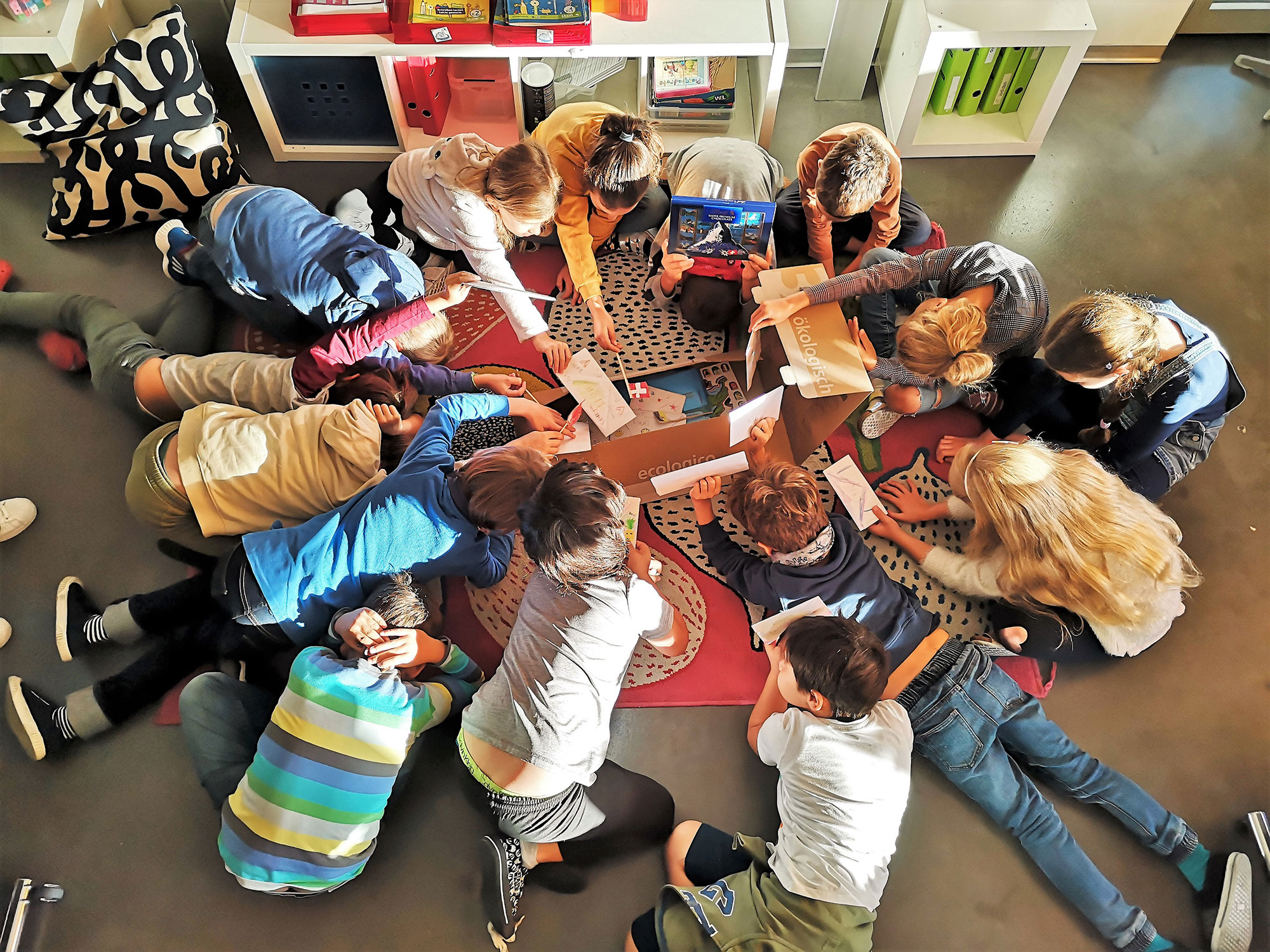 A group of pupils curiously bend over an opened parcel as part of the parcel swap activity.