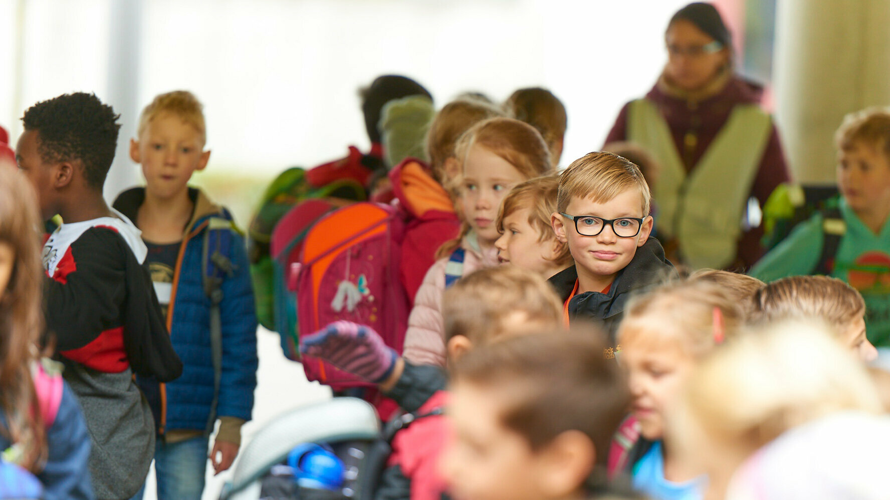 Gruppo di studenti in cui un bambino che indossa gli occhiali da vista guarda dritto verso l'obiettivo.