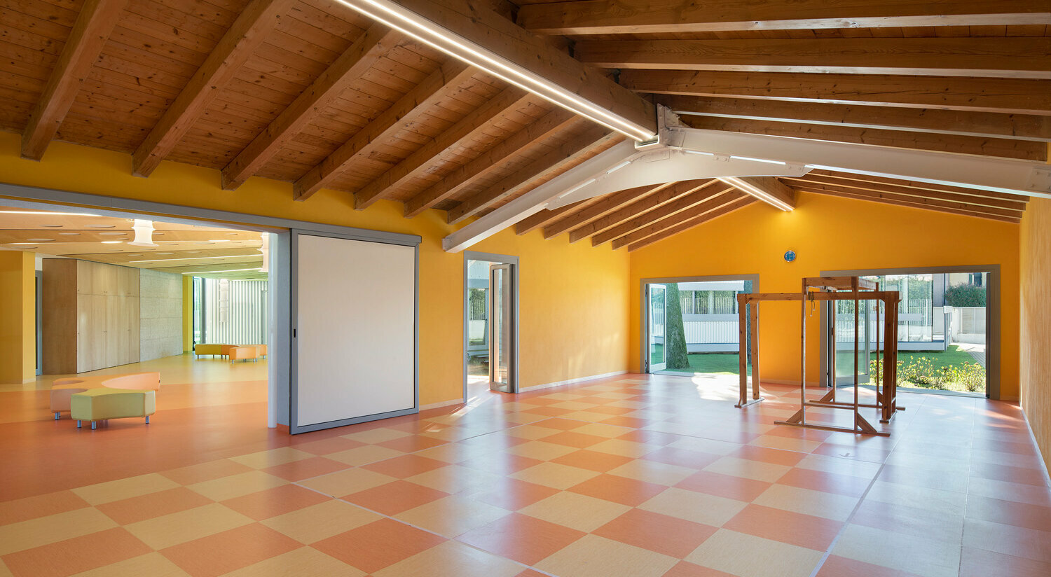 Una sala grande e moderna con finestre ampie, una pavimentazione sportiva e vari attrezzi sportivi. 