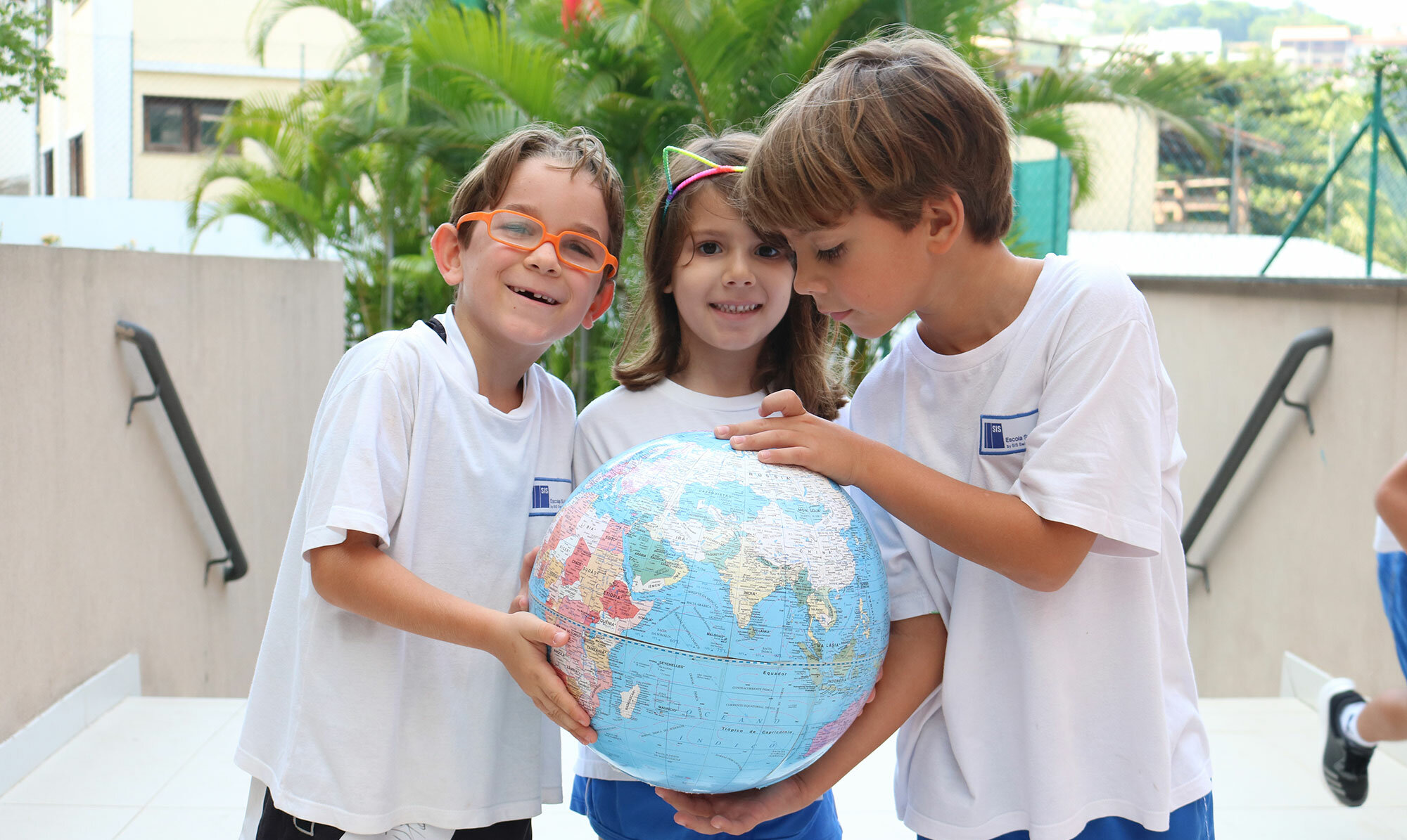 Tre bambini tengono insieme un mappamondo con le loro mani.